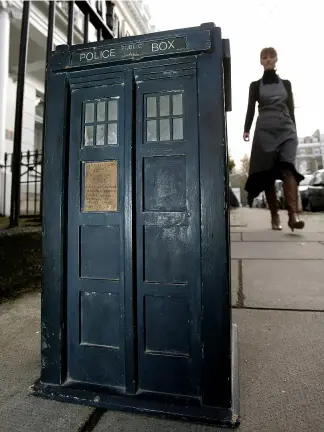  ?? KIRSTY WIGGLESWOR­TH/AP2005 ?? Woman walks by a scale model of the Tardis, London, Friday Dec. 9, 2005. The Tardis from the television series Doctor Who was sold at an auction for £10,000 in 2010.