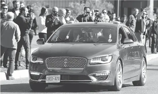  ?? JULIE OLIVER FILES ?? David Van Geyn, right, from Blackberry QNX, holds up his hands to demonstrat­e the driverless vehicle in which he took Ottawa Mayor Jim Watson, left, and others for a test ride last month at Kanata North Technology Park — the first-in-Canada...