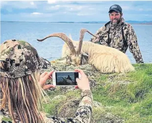  ??  ?? Controvers­ial hunter Larysa Switlyk takes a picture of her companion with the goat carcase on Islay.