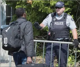  ?? Canadian Press file photo ?? An asylum seeker is questioned by an RCMP officer as he crosses the border into Canada from the United States near Champlain, N.Y., on Aug. 21, 2017.