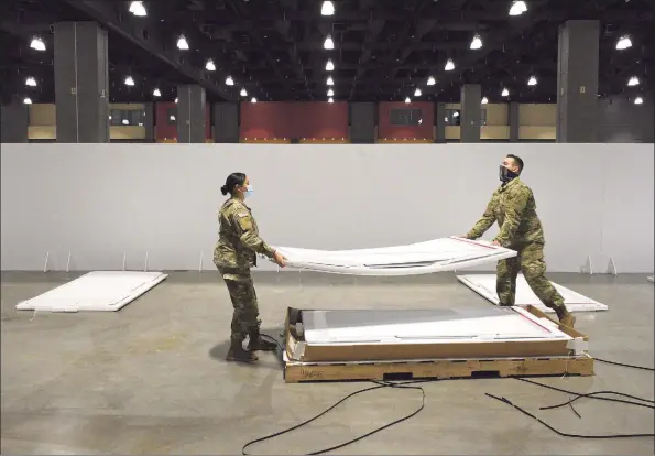  ?? H John Voorhees III / Hearst Connecticu­t Media ?? Spc. Samantha Pozo, left, of Danbury, and Spc. Daniel Lovallo, of West Haven, help the Connecticu­t National Guard set up a field hospital in the Connecticu­t Convention Center in Hartford. Hartford HealthCare will operate the site.