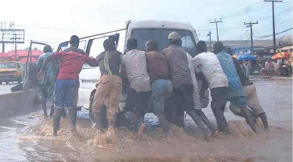  ??  ?? A motorist and others wading through flood after a heavy rainfall at Sango-ota, Abeokuta road, Ogun State, at the weekend.