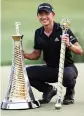  ?? LUKE WALKER Getty Images ?? Collin Morikawa of United States won the The Race to Dubai and The DP World Tour Championsh­ip trophies Sunday in Dubai, United Arab Emirates.