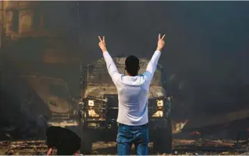  ?? ZAIN JAAFAR/GETTY-AFP ?? A Palestinia­n man flashes the victory sign at an Israeli military vehicle Wednesday in the West Bank.