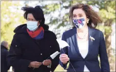  ?? Alex Wong / Getty Images ?? U.S. Speaker of the House Nancy Pelosi, D-Calif., right, and Washington, D.C., Mayor Muriel Bowser hold flags to plant at an outdoor art installati­on at the D.C. Armory parade ground in Washington on Monday.