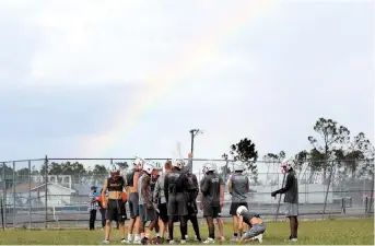  ??  ?? A rainbow appears as Mosley High football players practice outside their heavily damaged school, in the aftermath of Hurricane Michael in Lynn Haven. — IC