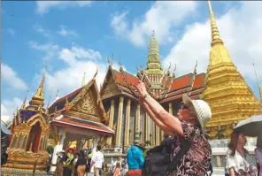  ?? MENG ZHONGDE / FOR CHINA DAILY ?? A Chinese tourist takes a photo at a Buddhist temple in Bangkok.