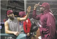  ?? Mitchell Leff / Getty Images ?? Philadelph­ia starter Jake Arrieta (left) high-fives Hector Neris after the Phils dusted Pittsburgh.