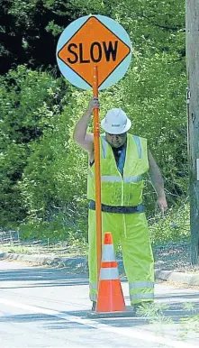  ?? BOSTON HERALD FILE ?? LOW YIELD: A flagman, above and below, warns oncoming traffic on Route 140 in Wrentham in June 2009. A 2008 law allowing civilian flaggers to replace police at work sites is failing to realize big savings in Massachuse­tts, according to a new report.