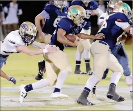  ?? Buy this photo at YumaSun.com PHOTO BY RANDY HOEFT/YUMA SUN ?? YUMA CATHOLIC’S JAYLEN BARNES (center) follows the block of Shamrocks lineman Johan Rodriguez (66) to pick up yardage as Queen Creek-Casteel’s Wyatt Reidhead (left) tries to make the tackle during the third quarter of Friday night’s game at Ricky Gwynn...