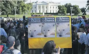  ??  ?? A protester holds up a sign during a rally against the United States backing out of the Paris climate accord Thursday at the White House in Washington.