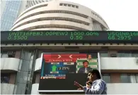  ?? — AFP FILE ?? A man walks by stock prices displayed on the facade of the Bombay Stock Exchange building in Mumbai.