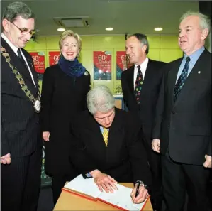  ??  ?? Bill Clinton signing a guestbook in First Active with, from left, Pearse O’Hanrahan, Hilary Clinton, Dermot Ahern, and John Quinlivan.