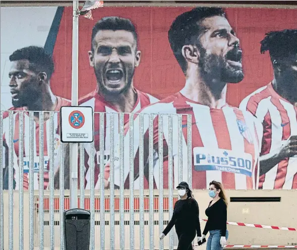  ??  ?? Dues dones passen per davant d’un mural de l’Atlètic a l’estadi Wanda Metropolit­ano de Madrid