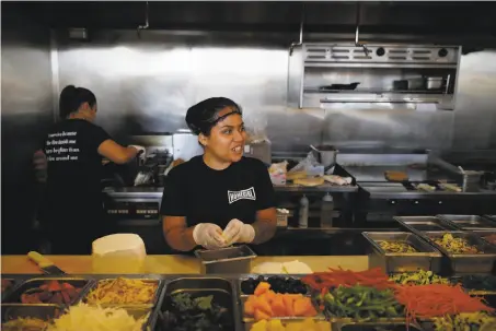  ?? Jae C. Hong / Associated Press ?? Maria Hidalgo, 26, talks to a co-worker while preparing food in the kitchen at Homegirl Cafe in the Chinatown section of L.A.