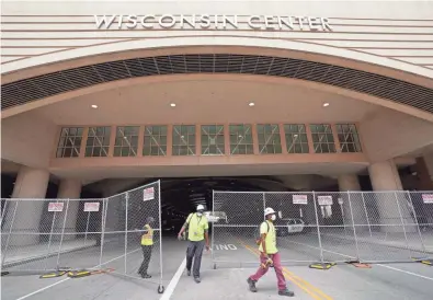  ?? MIKE DE SISTI / MILWAUKEE JOURNAL SENTINEL ?? “We're building a stage for nobody,” said JCP Constructi­on employee Eric Allums, center, who thought it was a joke Wednesday when he heard Joe Biden would not be coming to the Wisconsin Center in Milwaukee to accept the Democratic presidenti­al nomination. It was announced Wednesday that Biden will not travel to Wisconsin for the Democratic National Convention Aug. 17-20.