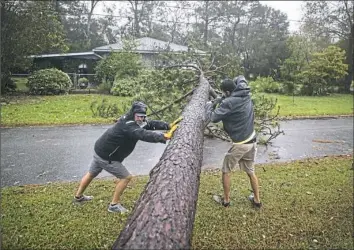  ?? Victor J. Blue/The New York Times ?? Lee Casteen, left, and Try Hinton use a chainsaw to clear a tree blocking a road that was downed as Hurricane Florence swept through the area in Wilmington, N.C., on Friday. The eye of the storm came ashore at Wrightsvil­le Beach, N.C., just east of Wilmington, with winds of about 90 mph.