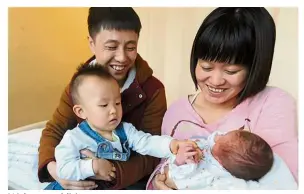  ?? — Lihao/China Daily ?? Welcome addition: A couple cuddling their children, an infant daughter and her 18-month-old elder brother, in Shenyang, Liaoning province.