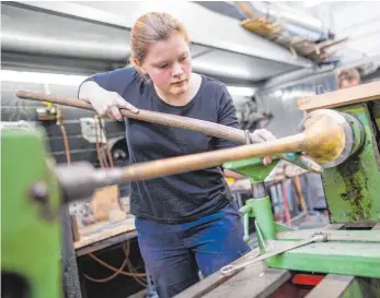  ?? FOTOS: CHRISTOPH SCHMIDT/DPA ?? Bei ihrer Arbeit braucht Lucia Zabinski durchaus auch Kraft: Die angehende Instrument­enmacherin bearbeitet ein Flügelhorn­stück an einer Drückbank.