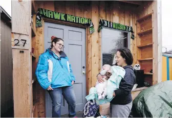  ?? ELAINE THOMPSON, THE ASSOCIATED PRESS ?? Eva Stough, right, holds her three-month-old baby, Kaysen Griffin, as she returns to her tiny house where a neighbour greets her at a homeless encampment in Seattle.