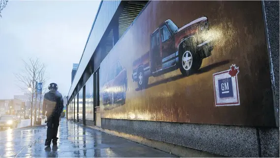  ?? COLE BURSTON/BLOOMBERG ?? A pedestrian walks past a GM mural in downtown Oshawa, Ont., on Monday. The job cuts there and in the U.S. are partly attributed to U.S. steel tariffs.