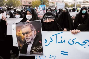  ?? ARASH KHAMOOSHI/THE NEW YORK TIMES ?? A protester holds an image of Mohsen Fakhrizade­h in Tehran, Iran. The nuclear scientist was killed in an ambush Friday.