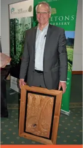  ??  ?? PF Olsen CEO, Peter Clark, with the handcarved NZ Forester of the Year award.