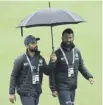  ??  ?? 0 India players examine the pitch as rain stops play