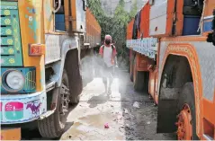  ?? PHOTO: REUTERS ?? Parked trucks being disinfecte­d on the outskirts of Kolkata