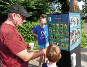  ??  ?? A father and his son review some of the cards of police officers Tuesday during National Night Out in Kennett Square.