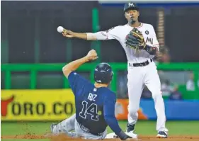  ?? THE ASSOCIATED PRESS ?? Miami Marlins second baseman Dee Gordon throws to first base as Rio Ruiz slides into second during the first inning of Friday’s game. Dansby Swanson was out at first on the innning-ending double play.