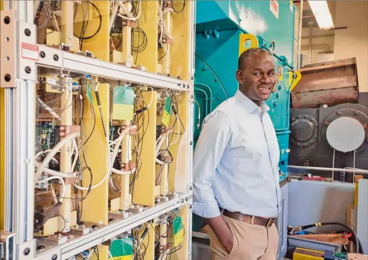  ?? Paul Buckowski / Times Union ?? Ibrahima Ndiaye, a technology manager for Power Electronic­s in the Electrical Systems Group at GE Research, poses for a photo in the GE grid lab on Feb. 1 in Niskayuna. Ndiaye is standing next to the company’s “Tower of Power,” on left, a multi-level wind power converter created through a five-year project with the U.S. Department of Energy Advanced Manufactur­ing Office’s Next Generation Electric Machines program. Members of Ndiaye’s team helped on the project.