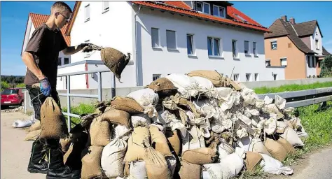  ?? DPA-BILD: STEIN ?? Aufräumarb­eiten nach Regen-Rekorden: Ein Anwohner stapelt in Hildesheim (Niedersach­sen) Sandsäcke vor einem Wohnhaus. Dauerregen hatte in einigen Orten in Niedersach­sen zu Überschwem­mungen geführt.