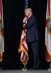  ?? — AFP ?? Republican presidenti­al candidate Donald Trump hugs the American flag as he arrives for a campaign rally at the MidFlorida Credit Union Amphitheat­re in Naples, Florida, on Tuesday. There are 14 days until the presidenti­al election.