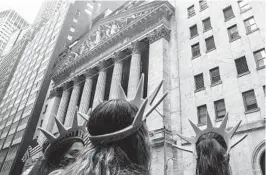  ?? BEBETO MATTHEWS AP ?? Visitors wear Lady Liberty souvenir headwear outside the New York Stock Exchange on Friday. The market was in turmoil during midday trading.