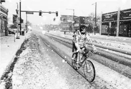  ?? MICAHEL CIAGLO/GETTY ?? A bicyclist makes his way down an icy and snowy street Sunday in Denver. The runways were closed just before noon Sunday at Denver Internatio­nal Airport.