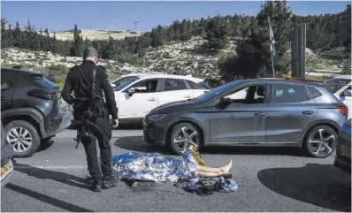  ?? AP ?? Un policía israelí, junto al cuerpo de un atacante palestino, en Cisjordani­a, ayer.