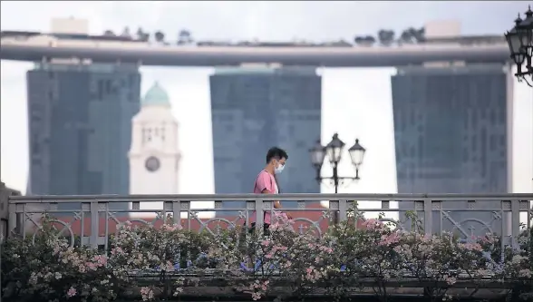  ?? Picture: EPA/How Hwee Young ?? Cases climb: A man wearing a protective face mask walks past the Marina Bay Sands buildings in Singapore