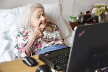  ?? THE ASSOCIATED PRESS PHOTO ?? Patient Louise Irving watches a laptop computer with her daughter’s morning wake-up video during her stay at The Hebrew Home of Riverdale, in New York, on March 25. The nursing home in the Bronx has started a pilot program in which relatives record...