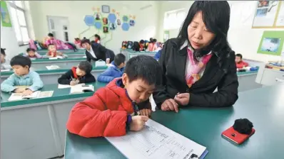  ?? LI XIN / XINHUA ?? A primary school pupil in Beijing registers on the list of children waiting for their parents to pick them up after school.