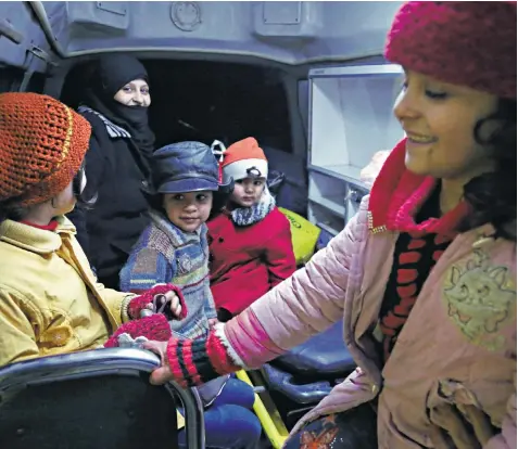  ??  ?? Syrian children being evacuated in an ambulance by Red Crescent medics in Douma in Eastern Ghouta on Boxing Day. Below, a suffering child cries during the evacuation