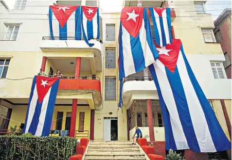  ??  ?? Cuban flags hang out to dry in Havana, above. Boris Johnson talks to RAF pilots in Barbados, above left. A house slides into the ocean in Ponte Vedra, Florida, below