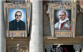  ?? AP ?? The tapestries of Roman Catholic Archbishop Oscar Romero, left, and Pope Paul VI hang from a balcony of the facade of St. Peter’s Basilica at the Vatican.