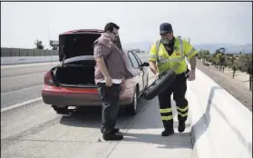  ?? ERIK VERDUZCO/LAS VEGAS REVIEW-JOURNAL FOLLOW @ERIK_VERDUZCO ?? Chuck Gianni, right, technician for a Nevada Department of Transporta­tion service, assists Tom Nobles with a flat tire on U.S. Highway 95 on in Las Vegas.