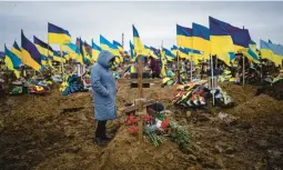  ?? EVGENIY MALOLETKA/AP ?? The wife of slain Ukrainian serviceman Serhiy Klymenko stands by his grave Friday in Kharkiv, Ukraine. Klymenko was killed by Russian shelling earlier in the week.