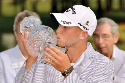  ??  ?? St. Jude Classic golf tournament winner Daniel Berger kisses his trophy during a ceremony after the tournament Sunday in Memphis, Tenn. (AP)