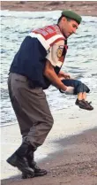  ?? AP ?? A police officer carries the body. Migrants died when boats carrying them to the Greek island of Kos capsized.