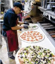  ?? CONTRIBUTE­D BY STEVE SCHAEFER ?? Felix Acosta makes some pies during the Friday night rush at Fini’s Pizzeria in Lawrencevi­lle, which, before the pandemic, didn’t take online orders.