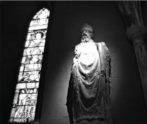  ??  ?? A statue of St. Patrick is seen Jan. 2 in St. Patrick’s Cathedral, Dublin. The stained glass window depicts the life of the fifth-century saint who brought Christiani­ty to Ireland.