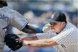  ?? SETH WENIG/THE ASSOCIATED PRESS ?? New York Yankees relief pitcher Joba Chamberlai­n gets a hand in his eye while tagging out the Blue Jays’ Jose Reyes during the first game of a doublehead­er at Yankee Stadium.
